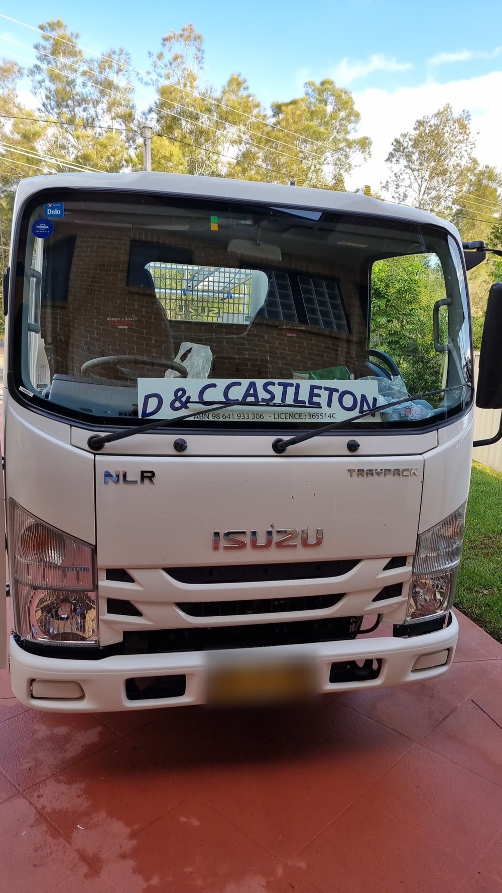 Front view of the white Isuzu truck with the D & C Castleton sign behind the windscreen
