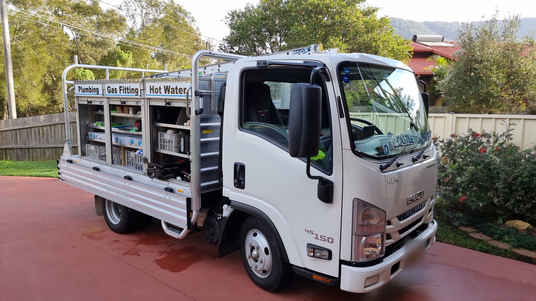 The D & C Castleton Isuzu work truck with its tray open, showing the Plumbing, Gas Fitting and Hot Water panels